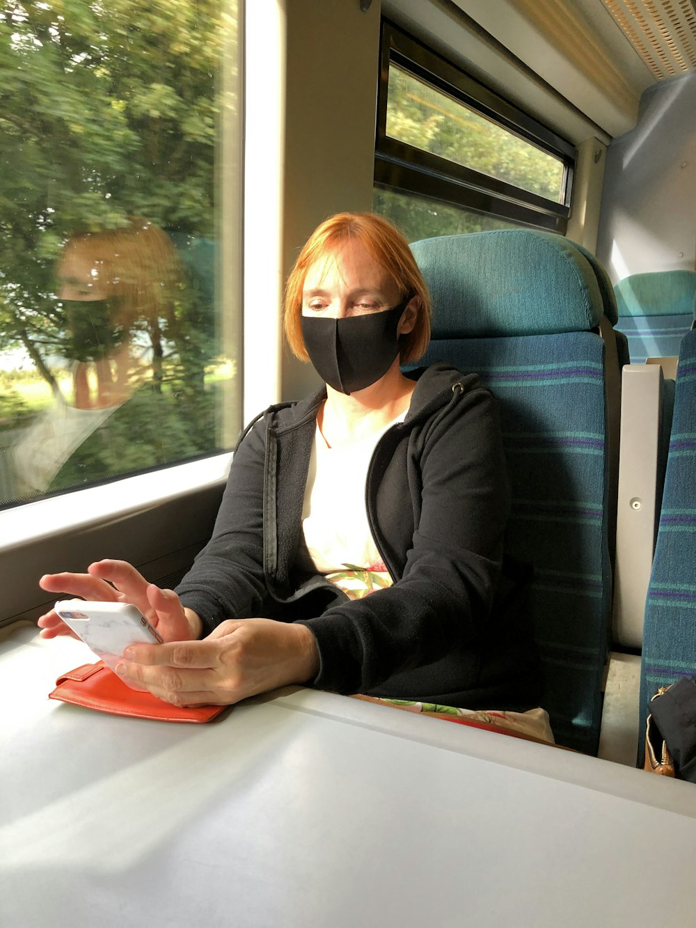a person wearing a mask and sitting on a train