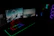 A glowing neon-lit gaming setup featuring a sleek PC tower and dual monitors in a dark room.
