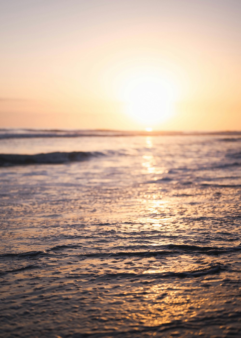 a body of water with waves and the sun setting