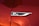 A close-up of a shiny, metallic badge with the text 'GT Line' on a surface with a glossy red paint finish. The badge is bordered by a sleek silver trim.