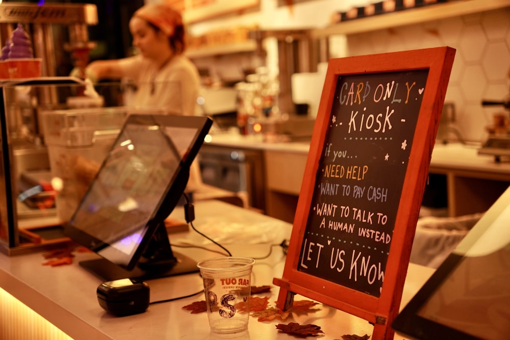 a person behind a counter with a laptop and a book