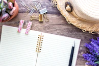 An open notebook with handwritten notes surrounded by scattered paper clips and washi tape rolls.