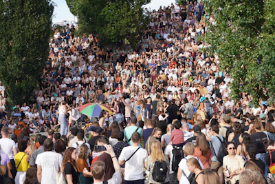 An outdoor cultural event with people gathered near the monumental staircase in the park.