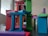 A collection of colorful wooden blocks is stacked in a playful and abstract manner, forming a miniature structure. The blocks vary in shape and color, creating a dynamic and vibrant arrangement.