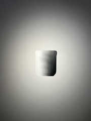 A minimalist, smooth cylindrical object with a matte finish is positioned centrally against a soft gradient background. The lighting creates a subtle shadow around the object, enhancing its three-dimensional appearance.