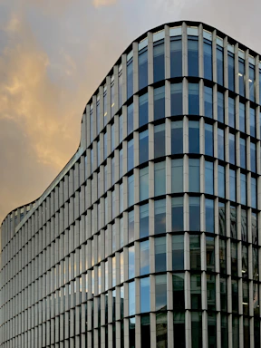 A sleek modern building with glass facades reflecting the sky, showcasing architectural detail.