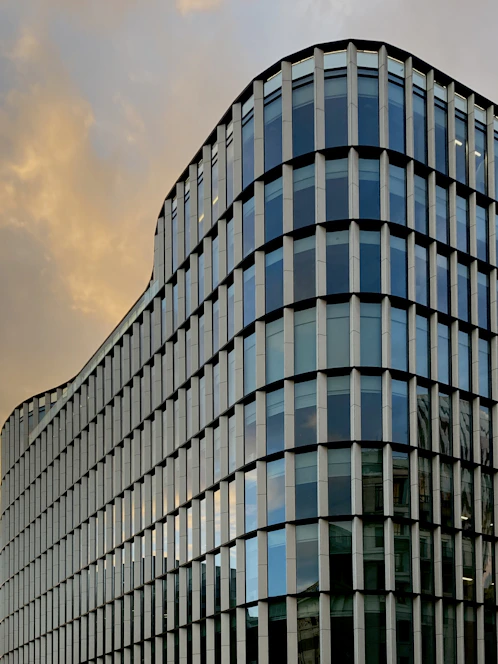A sleek modern building with glass facades reflecting the sky, showcasing innovative architectural design.
