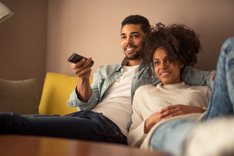 A couple sitting on a couch watching TV