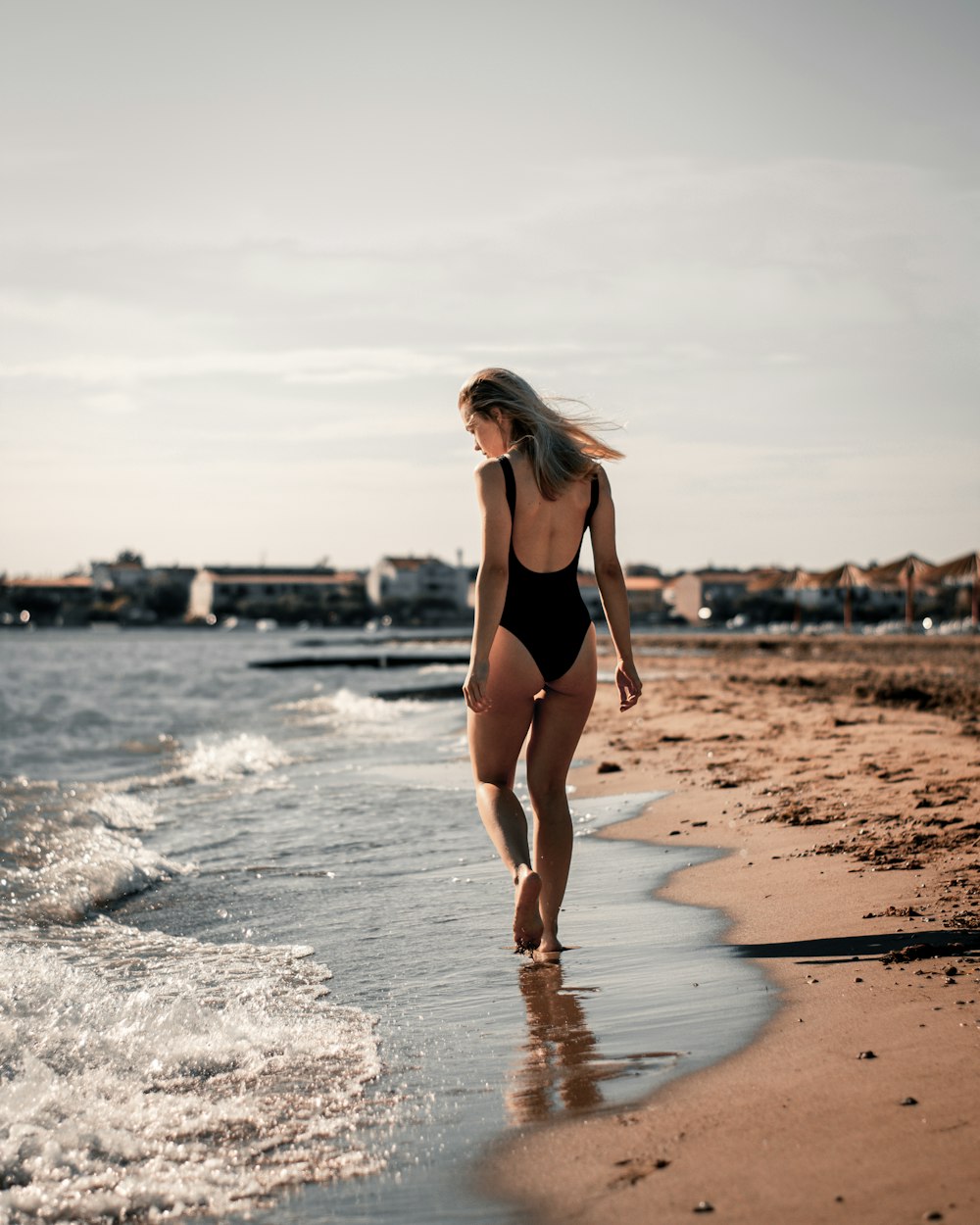 a woman in a swimsuit walking on a beach