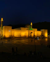 Evening lights illuminating the mosque with a warm golden glow.