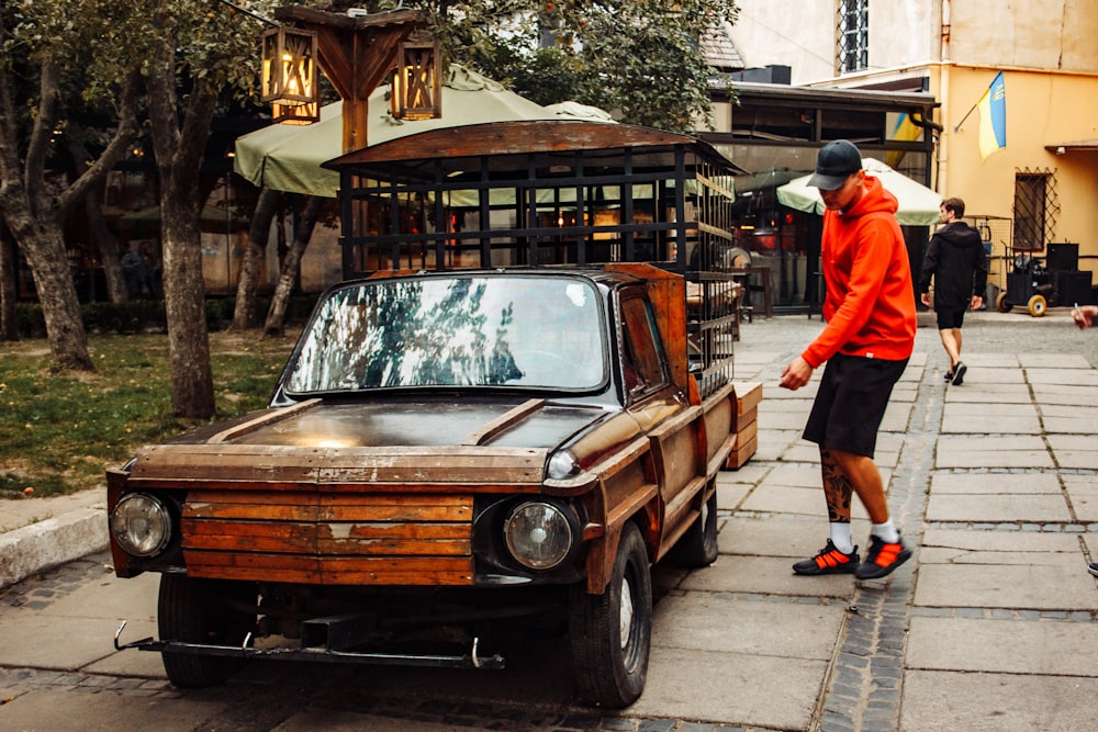 a man walking next to an old car