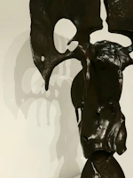 A close-up of a sleek, abstract bronze sculpture glowing softly under warm spotlight.