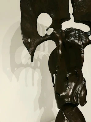 A close-up of a sleek, abstract bronze sculpture glowing softly under warm spotlight.