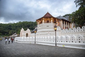 a white building with a gold roof with Temple of the Tooth in the background
