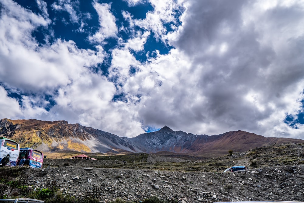 a group of vehicles parked in a rocky area with mountains in the background