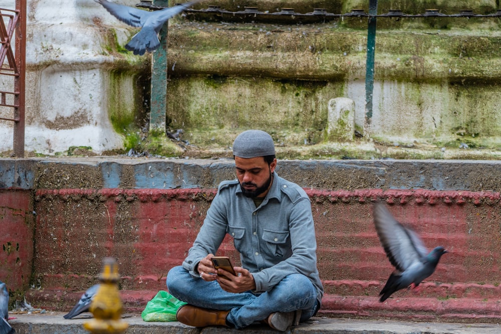a man sitting on the ground looking at his phone