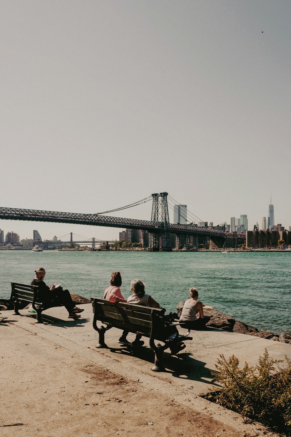 people sitting on benches in front of a body of water