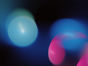 Abstract composition with blurred circles of light in soft blue and pink hues against a dark background, creating a dreamy and ethereal effect.