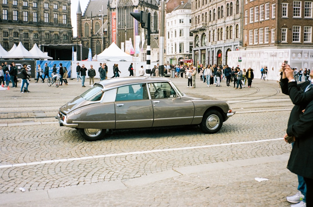 a car parked on a brick road with people and tents in the background