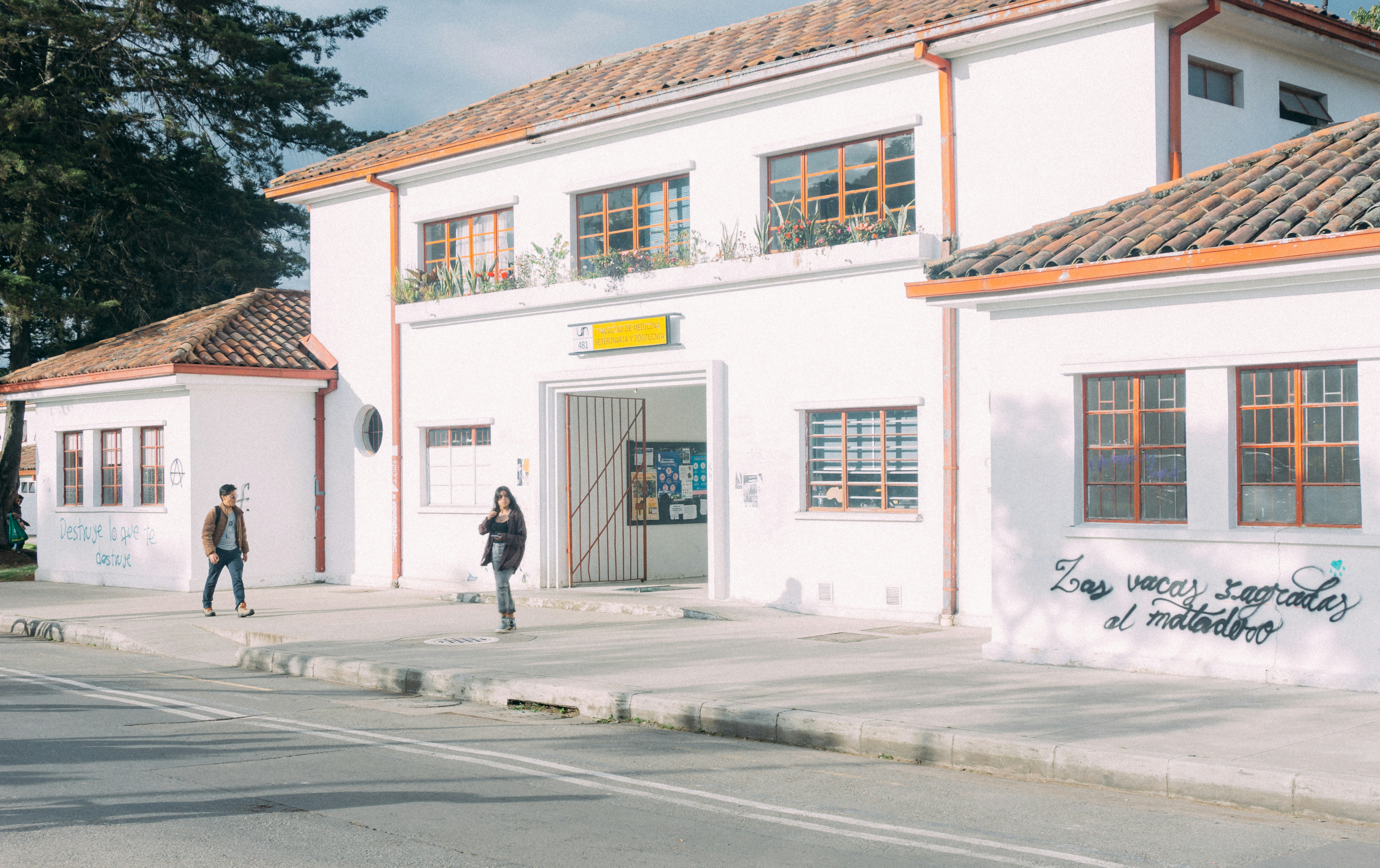 a couple of people walking on a sidewalk next to a building