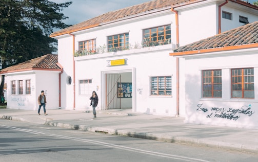 a couple of people walking on a sidewalk next to a building