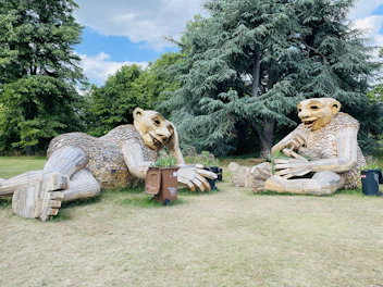 Outdoor lawn sculpture shaped like a playful animal, set in a garden.