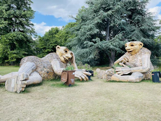 Outdoor lawn sculpture shaped like a playful animal, set in a garden.