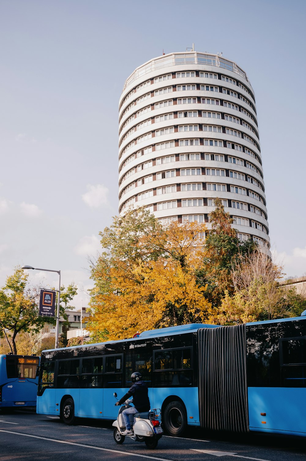 a person riding a scooter next to a tall building with City Hall, London in the background