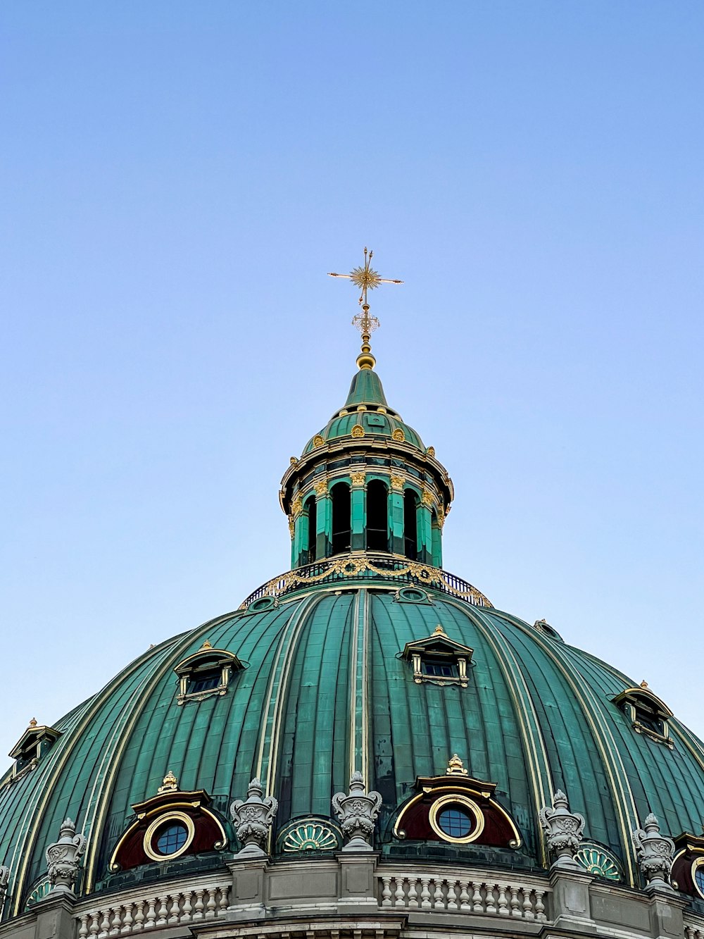 a building with a green roof and a cross on top