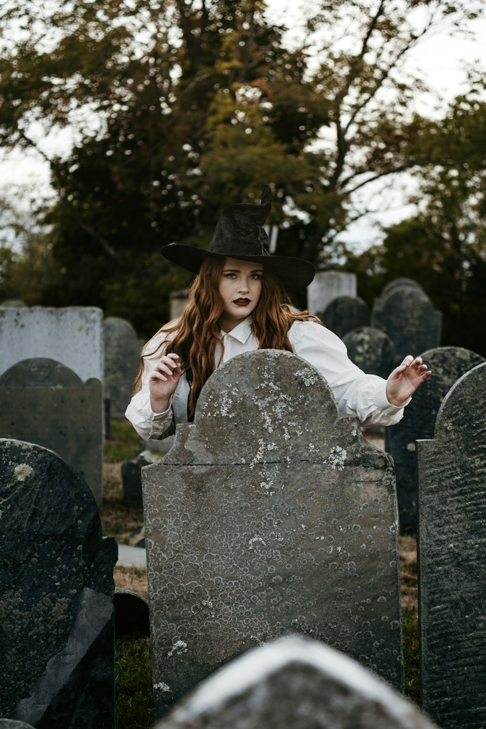 a person in a hat sitting on a stone pillar