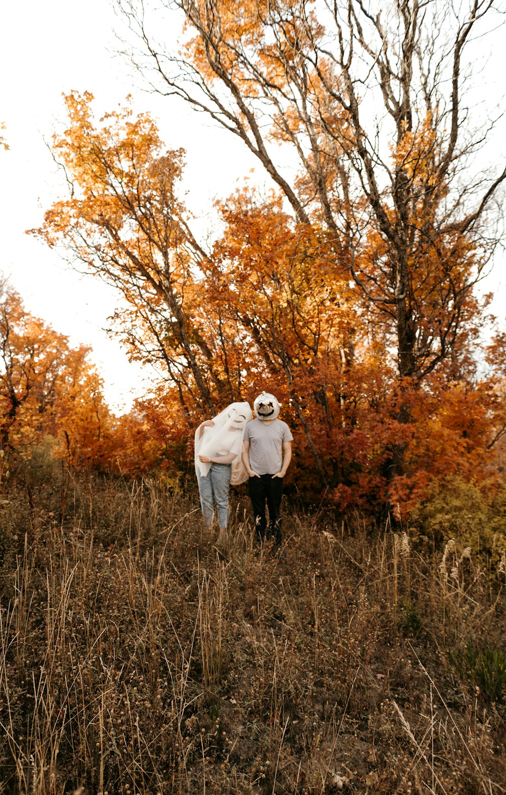 a man and woman standing in a field of tall grass