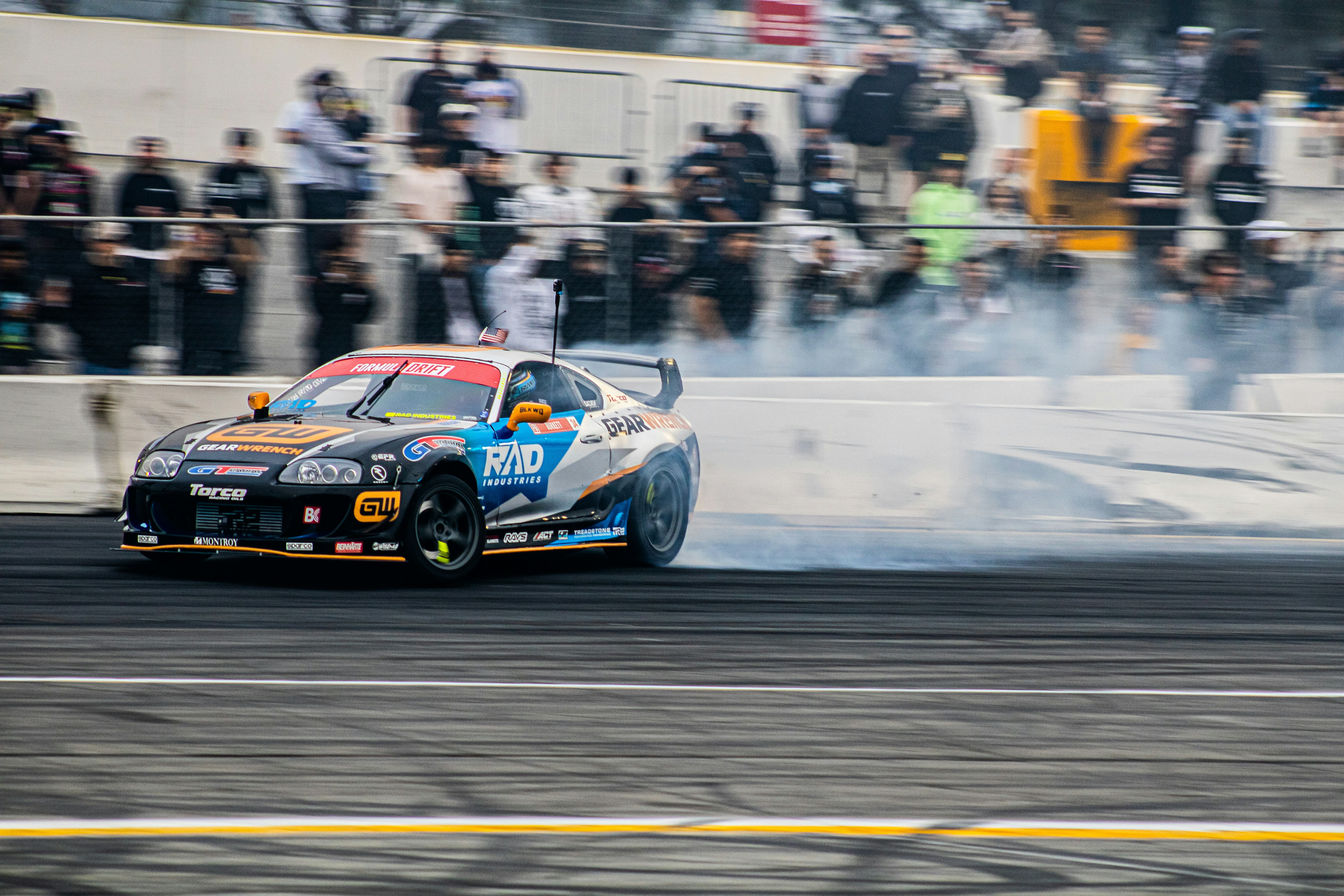 Racing car drifting on circuit track with smoke trails, dramatic action shot under stadium lights