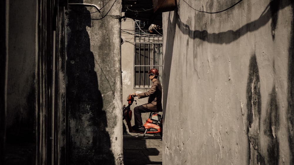 a man sitting on a scooter in a narrow alley
