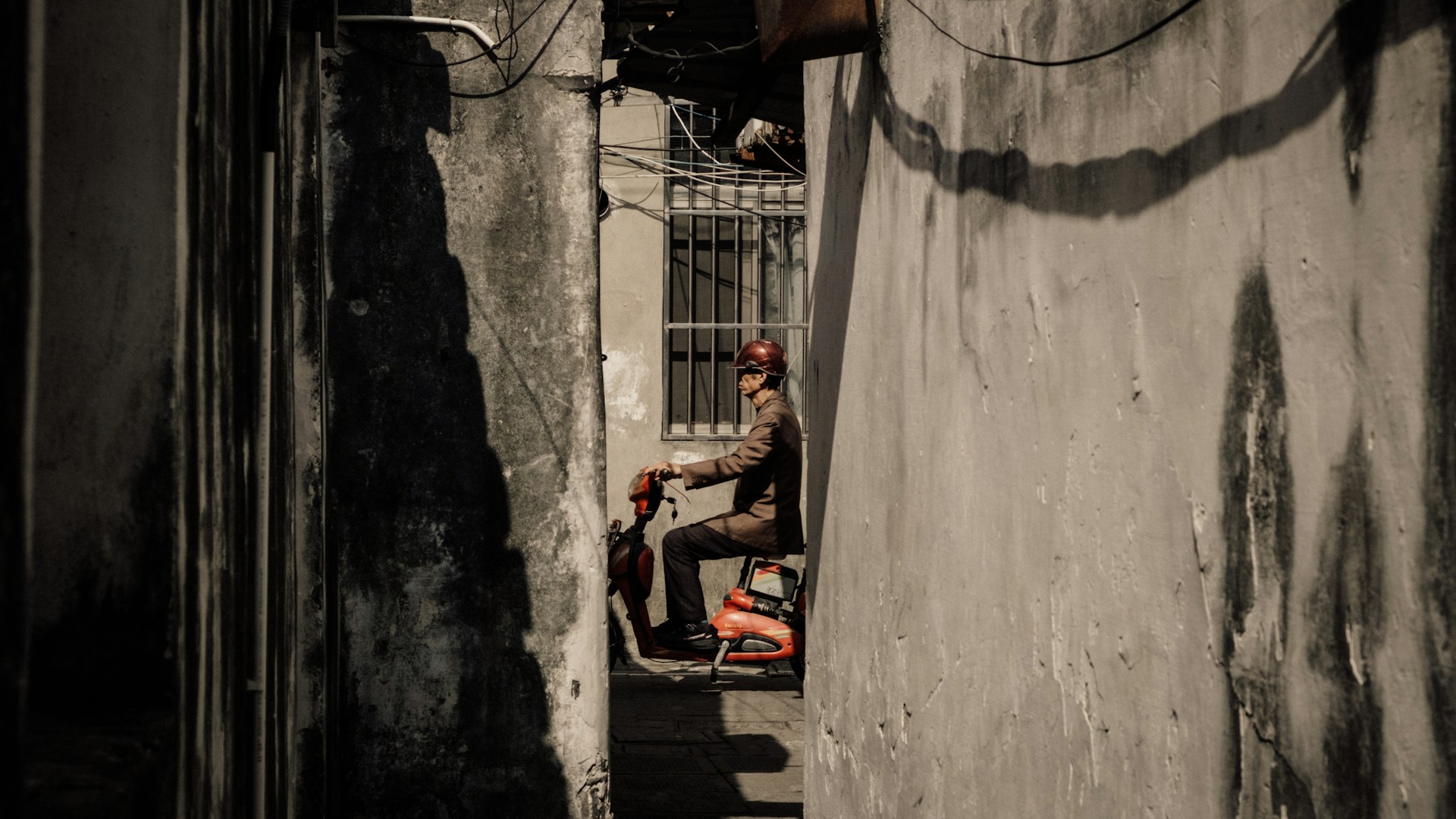 a man sitting on a scooter in a narrow alley