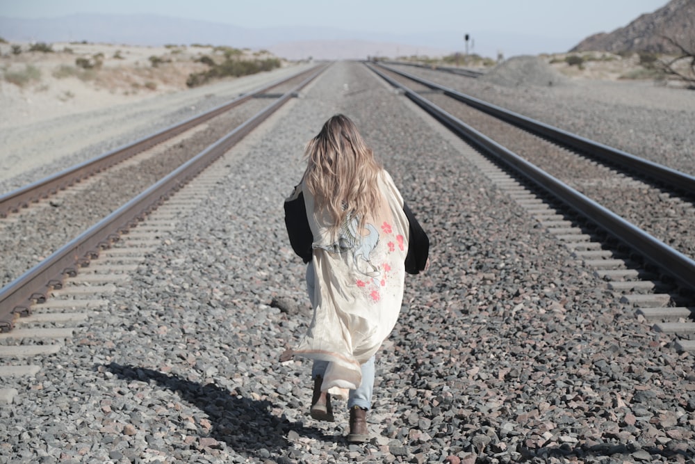 a girl walking on a railroad track