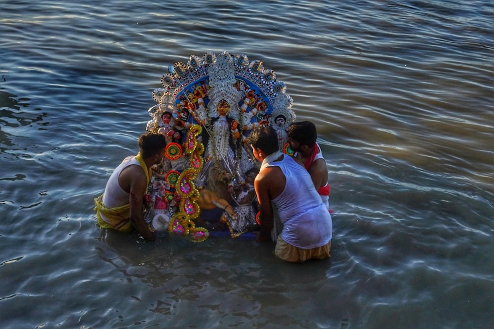 a group of people in the water with a large colorful umbrella