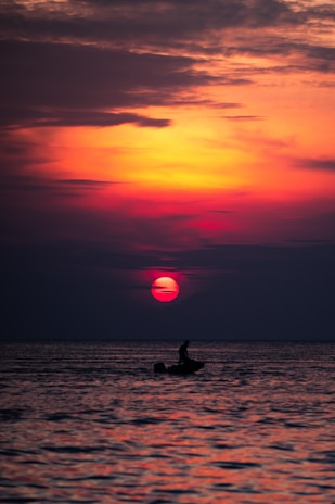 Sunset glow painting the sky orange as a trolling boat returns to shore with a successful day's catch.
