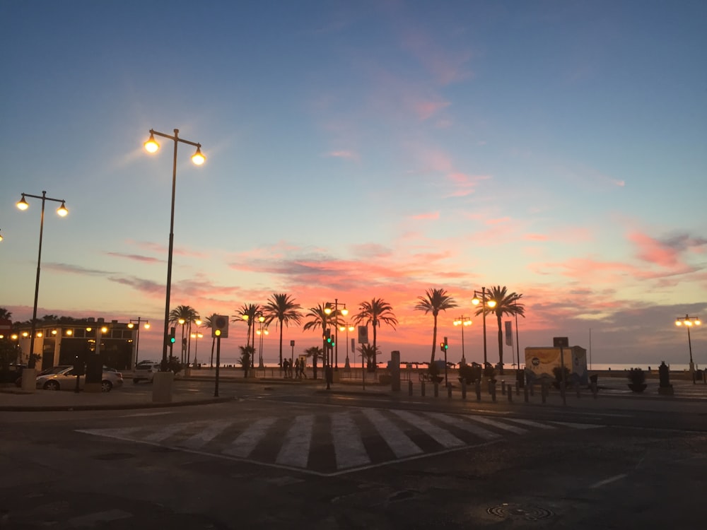 a parking lot with palm trees and a sunset