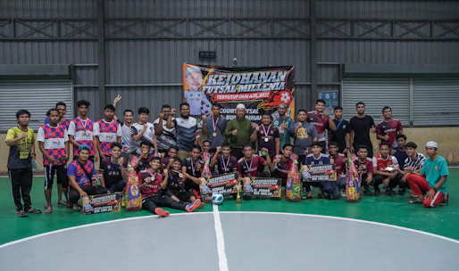 Coaches and athletes celebrating a futsal victory with joyful expressions in an indoor court.