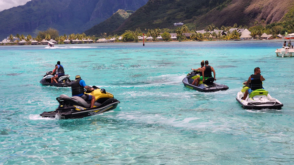 A group of happy tourists riding jet skis on the sparkling turquoise waters of Dar es Salaam under a bright sunny sky.