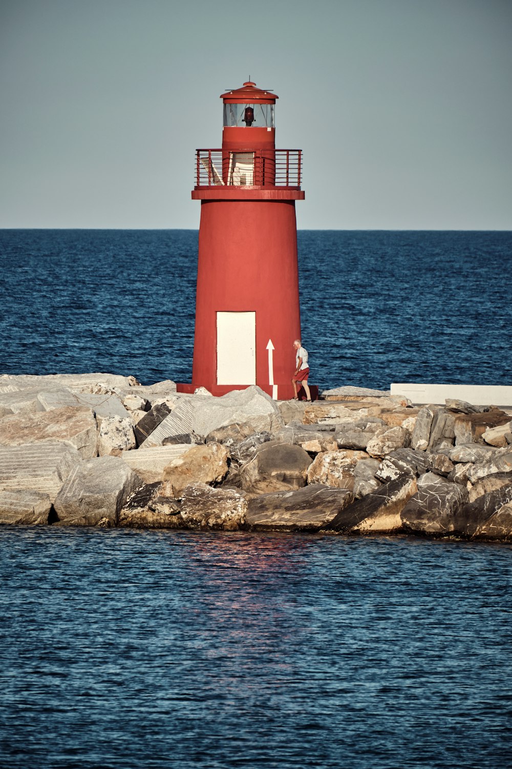 a red and white lighthouse on a rocky shore