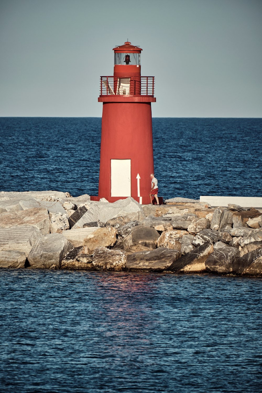 Un faro rojo y blanco en una orilla rocosa