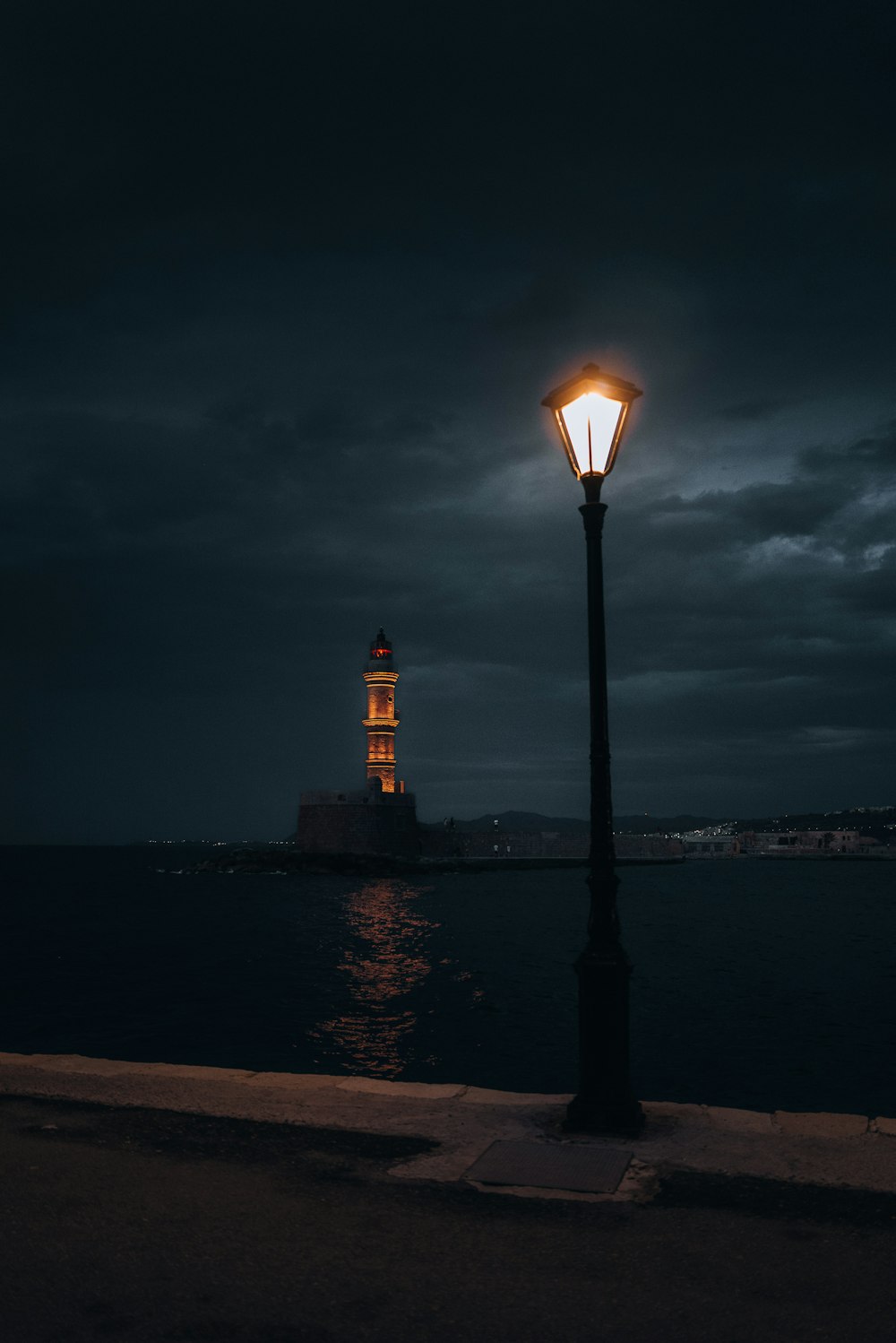 a light post with a lighthouse in the background