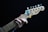 A close-up of a hand playing a Fender Telecaster guitar. The fingers are positioned on the fretboard, and there is a blue and yellow guitar pick holder attached to the headstock. The guitar is set against a dark background.