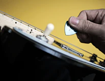 Close-up of hands easily swapping a colorful pickguard on an electric guitar.
