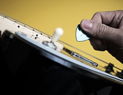 Close-up of a hand selecting a guitar pick from a colorful assortment on a wooden table.