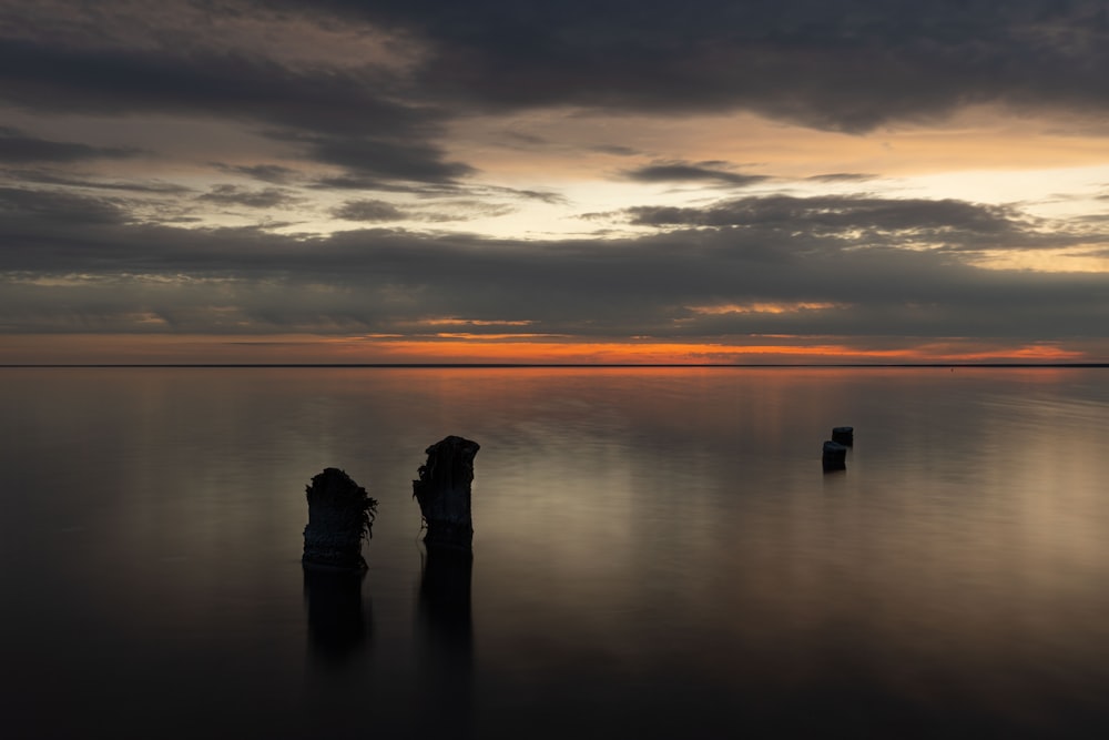 a body of water with rocks in it and a cloudy sky above