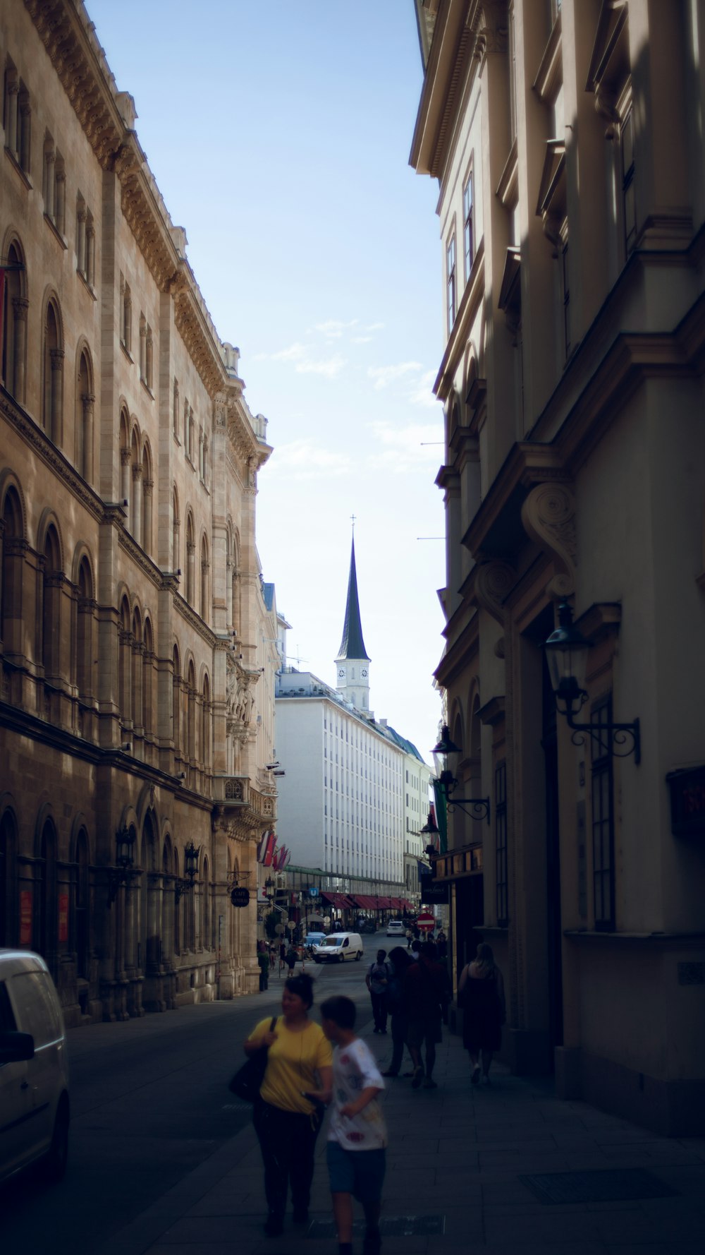 people walking on a street between buildings