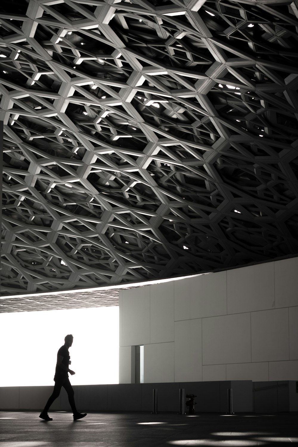 a person walking in a large room with a large ceiling of lights