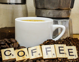 A steaming cup of espresso surrounded by coffee beans and a vintage coffee grinder